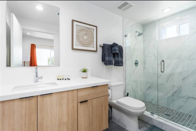 bathroom featuring vanity, a shower with shower door, and toilet