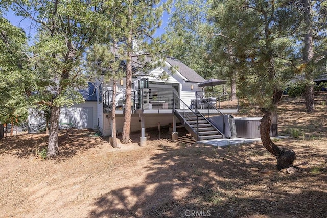 rear view of property with a hot tub and a wooden deck