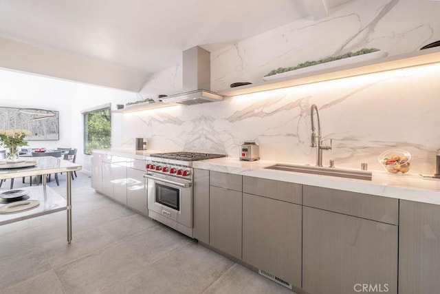 kitchen with decorative backsplash, luxury range, island range hood, sink, and gray cabinets