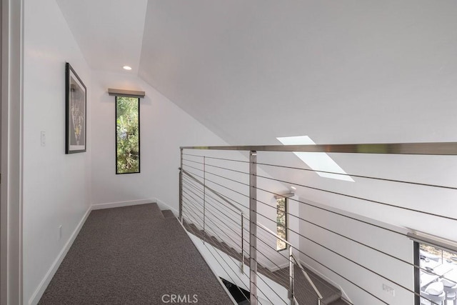 hall with dark carpet and vaulted ceiling