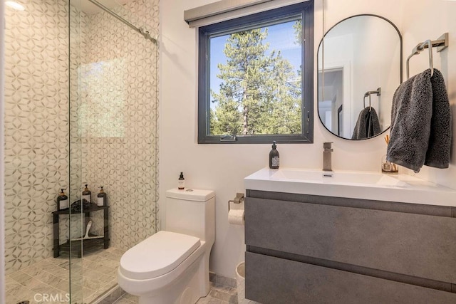 bathroom with vanity, toilet, and a tile shower