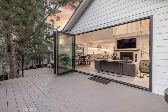 wooden terrace with an outdoor living space with a fireplace