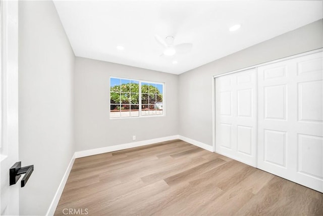 unfurnished bedroom featuring ceiling fan, a closet, and light wood-type flooring