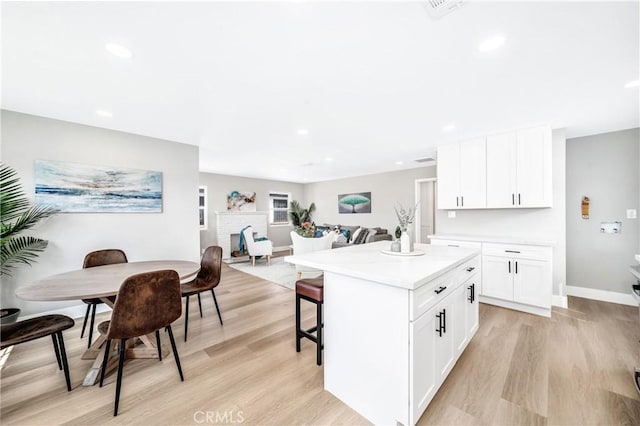 kitchen featuring white cabinetry, a kitchen island, a breakfast bar area, and light hardwood / wood-style floors