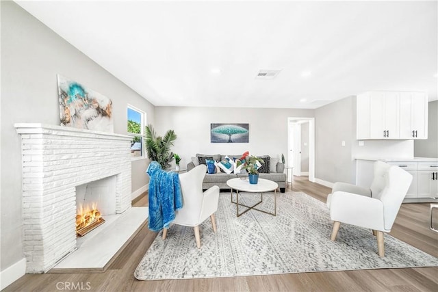 living room featuring a brick fireplace and light hardwood / wood-style flooring