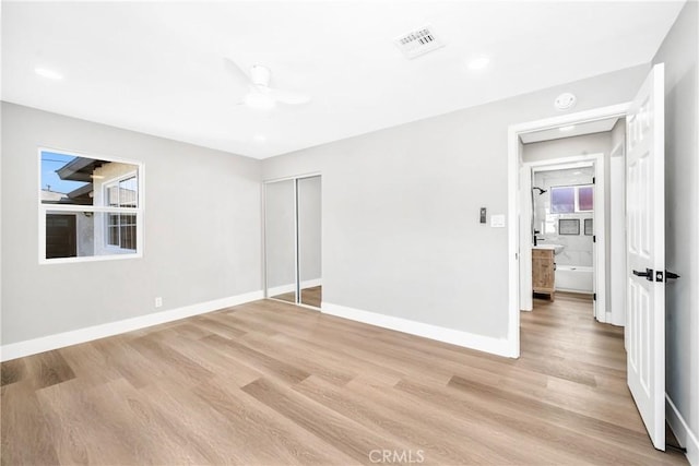 unfurnished bedroom with ceiling fan, light wood-type flooring, and a closet