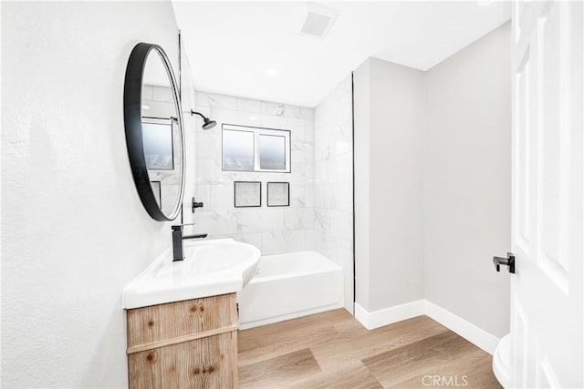 bathroom featuring vanity, hardwood / wood-style floors, and tiled shower / bath combo