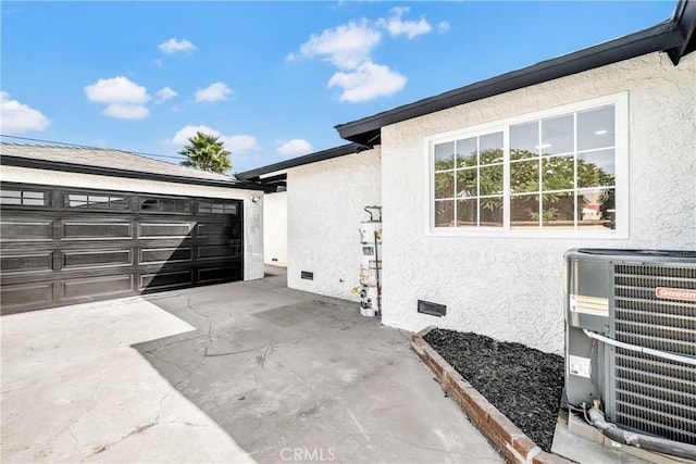 view of side of home featuring a garage, gas water heater, an outbuilding, and central AC unit