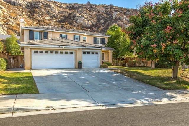 front facade with a mountain view, a garage, and a front lawn