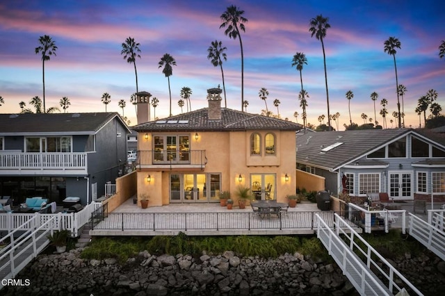 back house at dusk featuring a balcony and a deck