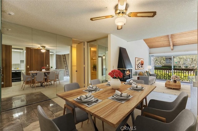 dining space featuring ceiling fan, lofted ceiling with beams, and a textured ceiling