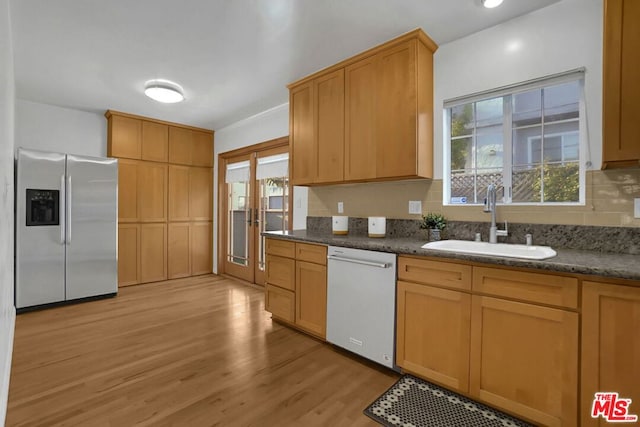 kitchen featuring stainless steel fridge with ice dispenser, white dishwasher, a healthy amount of sunlight, and sink