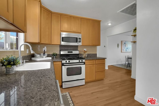 kitchen with tasteful backsplash, light hardwood / wood-style flooring, white gas stove, and sink