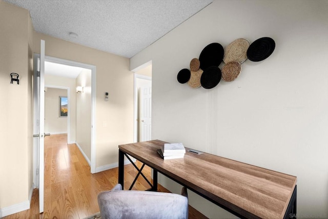 home office with hardwood / wood-style floors and a textured ceiling