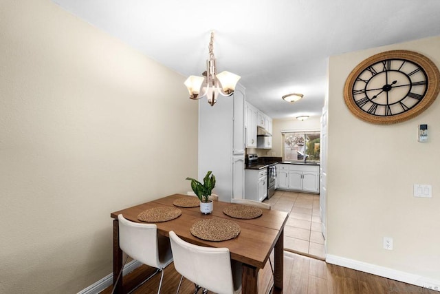 dining area with a chandelier, light wood-type flooring, and sink