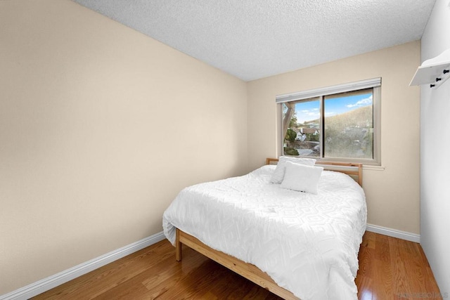 bedroom with a textured ceiling and hardwood / wood-style flooring