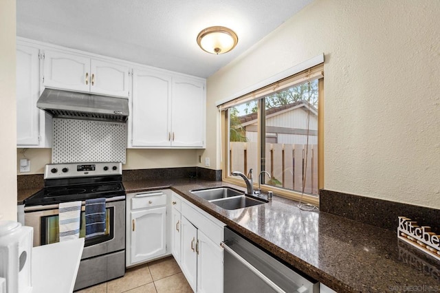 kitchen with sink, ventilation hood, dark stone countertops, white cabinets, and appliances with stainless steel finishes