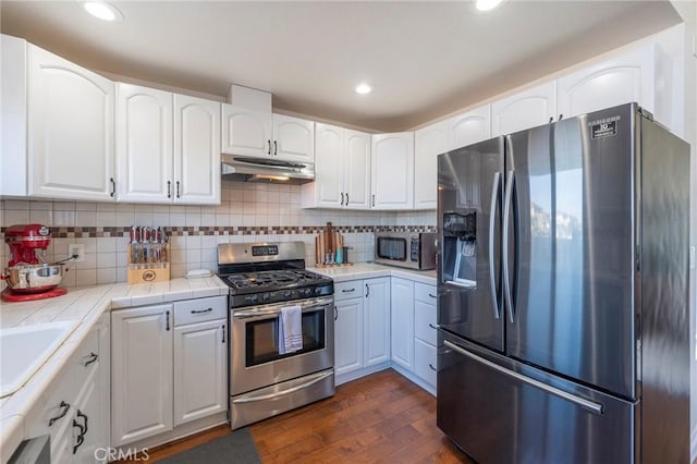 kitchen featuring dark hardwood / wood-style flooring, stainless steel appliances, white cabinetry, and tile counters