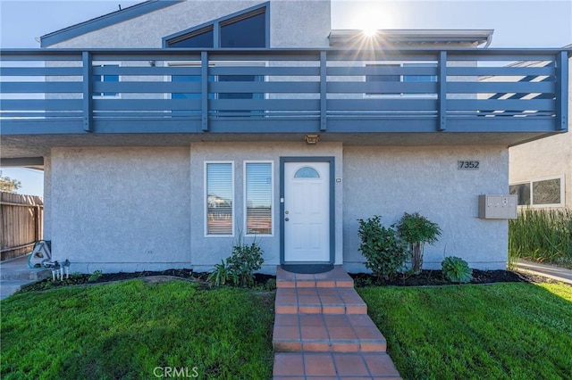 doorway to property with a balcony and a lawn