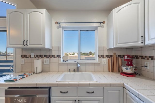 kitchen with decorative backsplash, white cabinetry, sink, and tile countertops