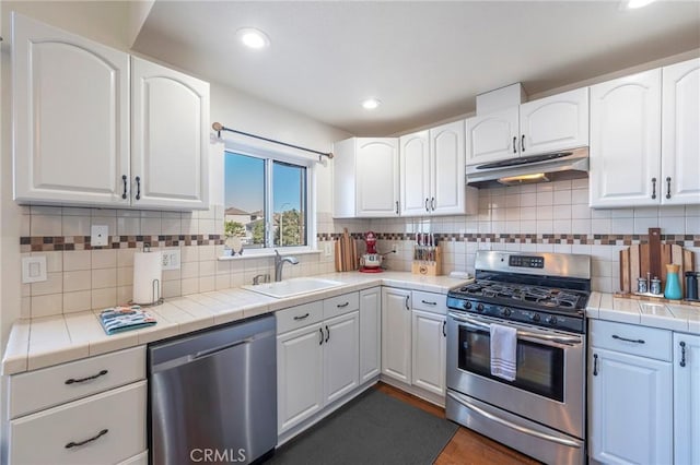 kitchen featuring backsplash, sink, appliances with stainless steel finishes, tile counters, and white cabinetry