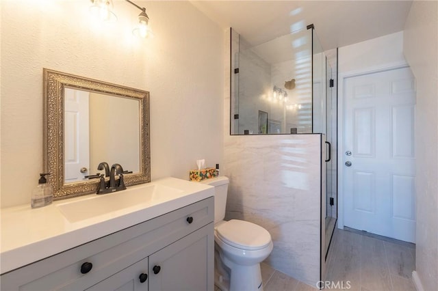 bathroom featuring walk in shower, hardwood / wood-style flooring, vanity, and toilet