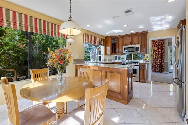 kitchen featuring kitchen peninsula, decorative backsplash, hanging light fixtures, light stone countertops, and stainless steel appliances