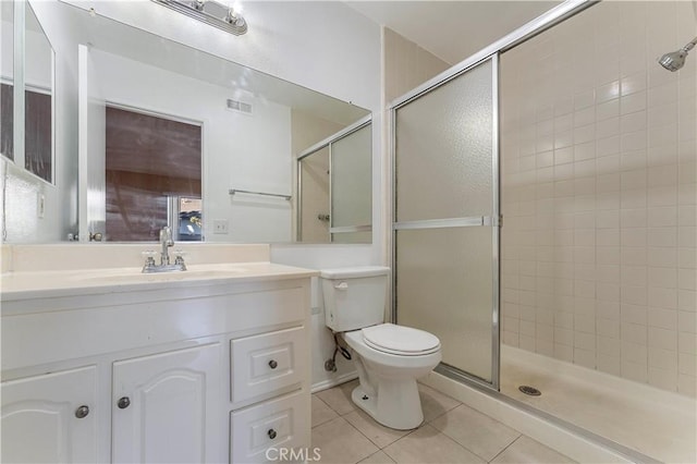 bathroom with tile patterned floors, vanity, a shower with shower door, and toilet