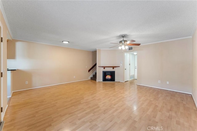 unfurnished living room with light hardwood / wood-style flooring, a textured ceiling, and ornamental molding