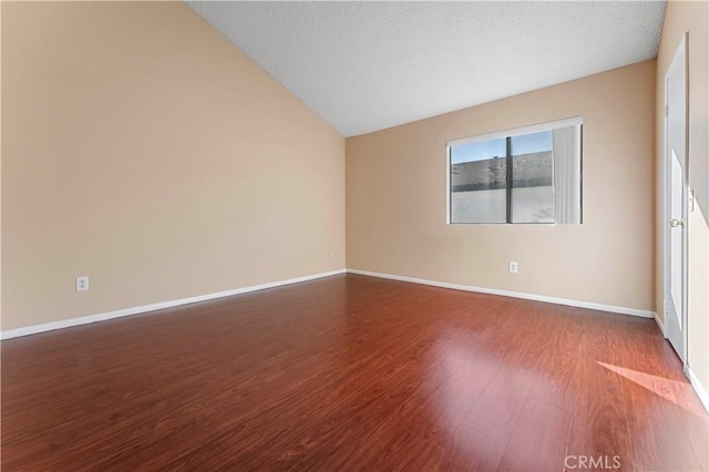 unfurnished room with hardwood / wood-style floors, a textured ceiling, and vaulted ceiling