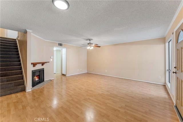 unfurnished living room featuring a textured ceiling, light hardwood / wood-style flooring, ceiling fan, and ornamental molding