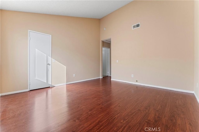 spare room featuring dark hardwood / wood-style floors and high vaulted ceiling