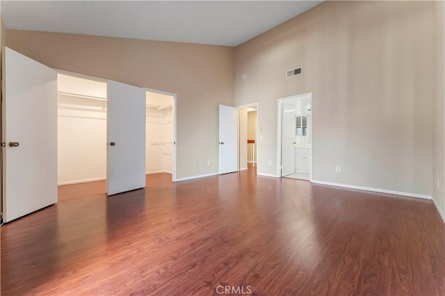 unfurnished bedroom with dark hardwood / wood-style floors, a spacious closet, high vaulted ceiling, and a closet