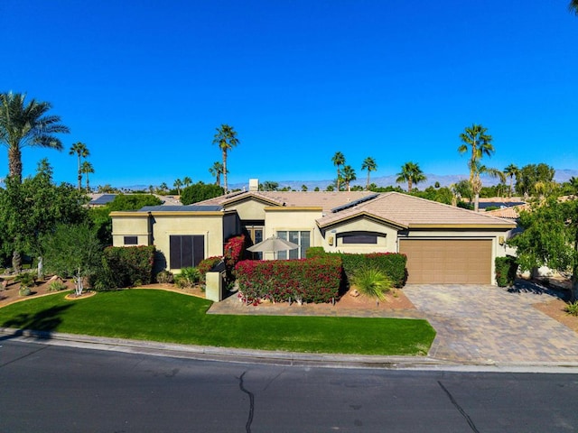 ranch-style home with solar panels, a front lawn, and a garage