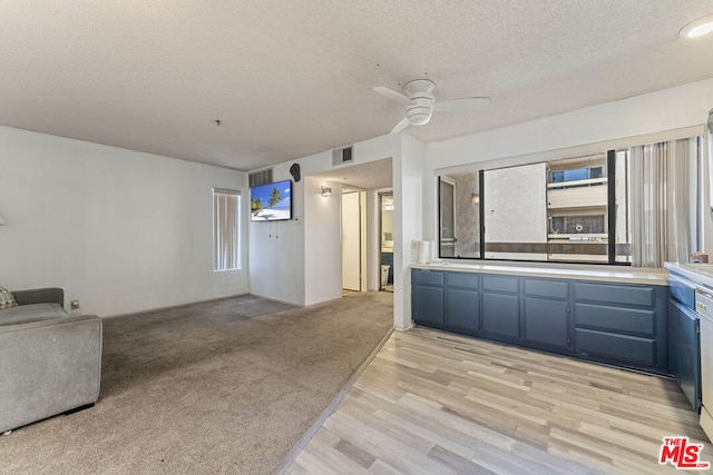 unfurnished living room with ceiling fan, a textured ceiling, and light hardwood / wood-style flooring