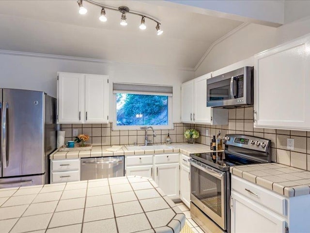 kitchen featuring tile counters, white cabinets, stainless steel appliances, and sink