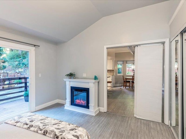 unfurnished bedroom with access to outside, a closet, vaulted ceiling, and light wood-type flooring