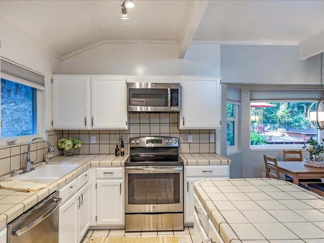 kitchen with appliances with stainless steel finishes, tile countertops, and sink