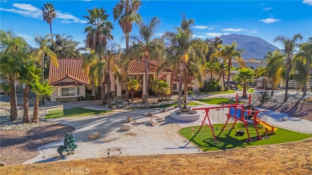 view of property's community featuring a mountain view, a playground, and a lawn