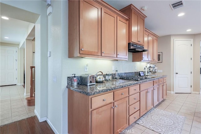 kitchen featuring light tile patterned flooring, dark stone counters, and stainless steel gas stovetop