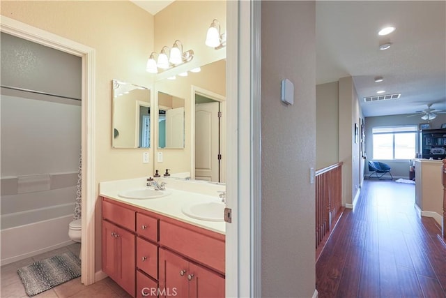 bathroom featuring hardwood / wood-style flooring, ceiling fan, vanity, a tub, and toilet