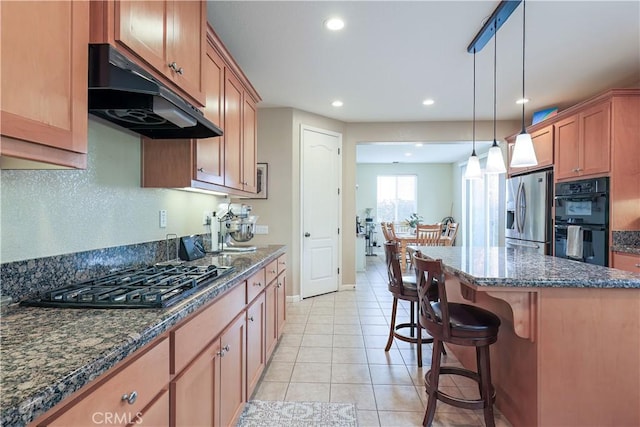 kitchen featuring light tile patterned flooring, a breakfast bar, appliances with stainless steel finishes, a kitchen island, and pendant lighting