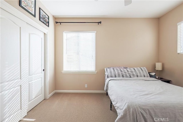 bedroom featuring multiple windows, light carpet, and a closet