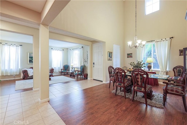 dining area with a towering ceiling, a chandelier, and light tile patterned flooring