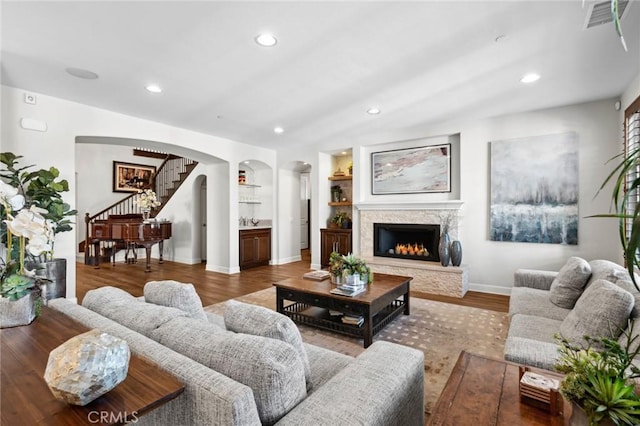 living room featuring a fireplace, built in features, and hardwood / wood-style flooring