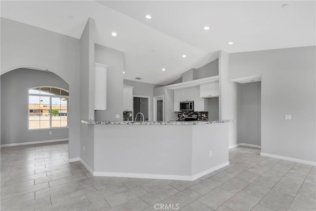 kitchen with light stone countertops, kitchen peninsula, high vaulted ceiling, white cabinetry, and light tile patterned flooring