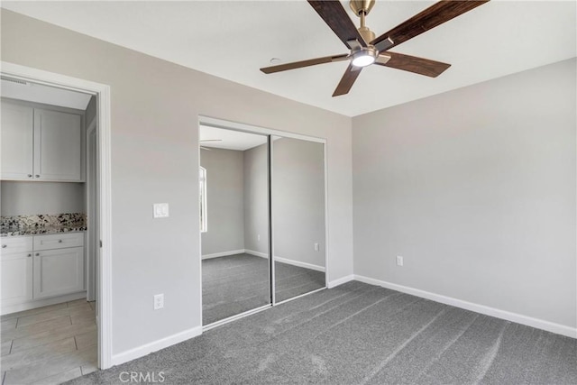 unfurnished bedroom featuring carpet floors, a closet, and ceiling fan