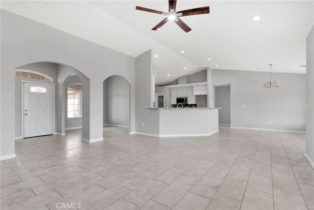 unfurnished living room with high vaulted ceiling and ceiling fan with notable chandelier