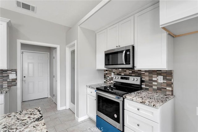 kitchen featuring light stone countertops, appliances with stainless steel finishes, backsplash, light tile patterned floors, and white cabinets