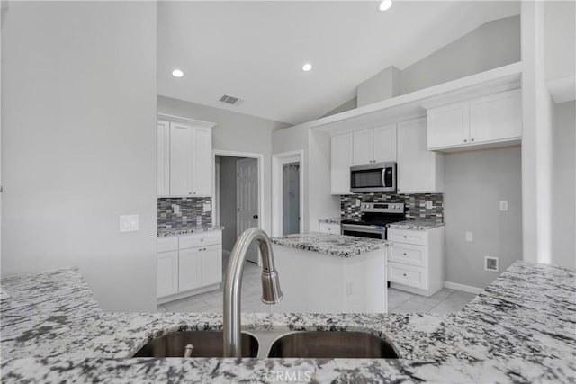 kitchen with appliances with stainless steel finishes, tasteful backsplash, lofted ceiling, and sink